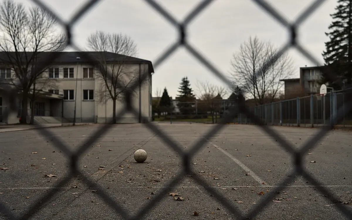 Cour de récréation vide vue à travers un grillage
